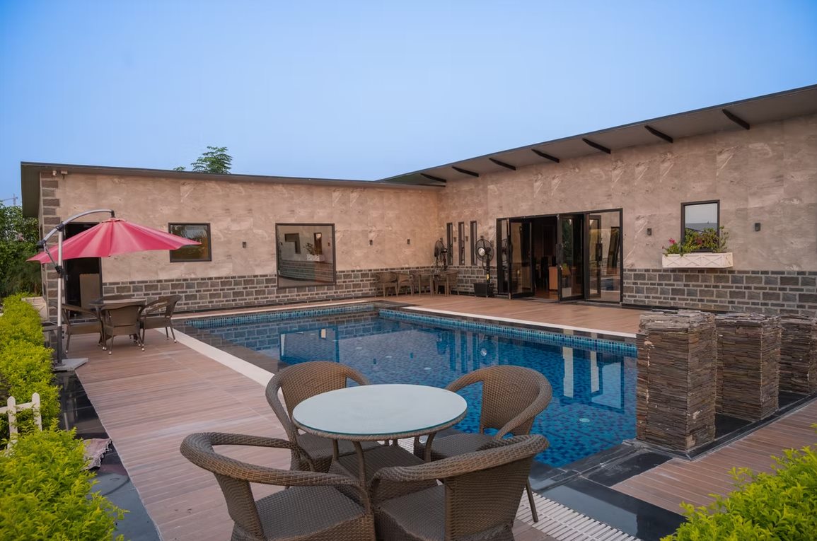 The pool courtyard under a clear blue sky, with wicker seating on the deck