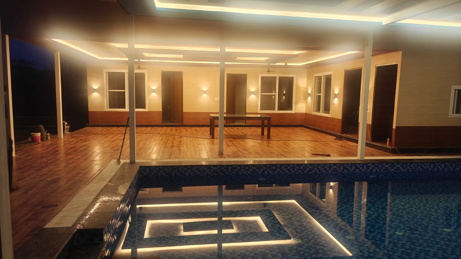 The same courtyard at night, the pool glowing from lights set into the water